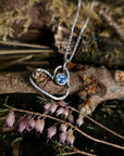 Heart-shaped necklace with a blue topaz gemstone on a natural background