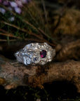 Silver ring with a red gemstone on a natural background