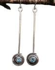 Silver earrings with blue gemstones hanging on a branch. Handmade in Northern Ireland