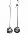Pair of silver earrings with blue topaz gemstones on a white background