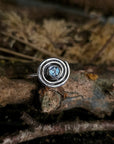 Silver ring with a blue gemstone on a natural background, ancient spiral, irish design