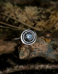 Silver ring with a blue gemstone on a textured surface, ancient irish design, spiral