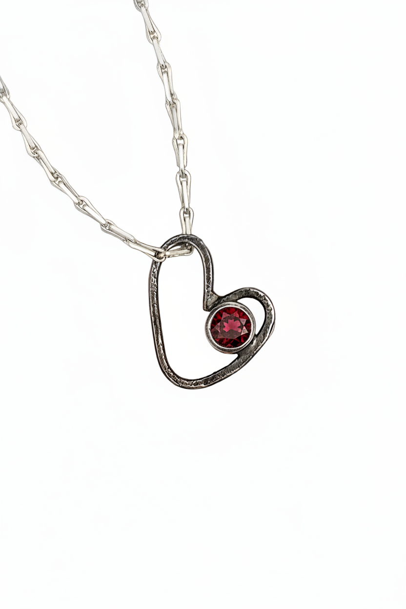 Heart-shaped pendant with a purple gemstone on a white background