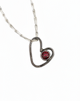 Heart-shaped pendant with a purple gemstone on a white background