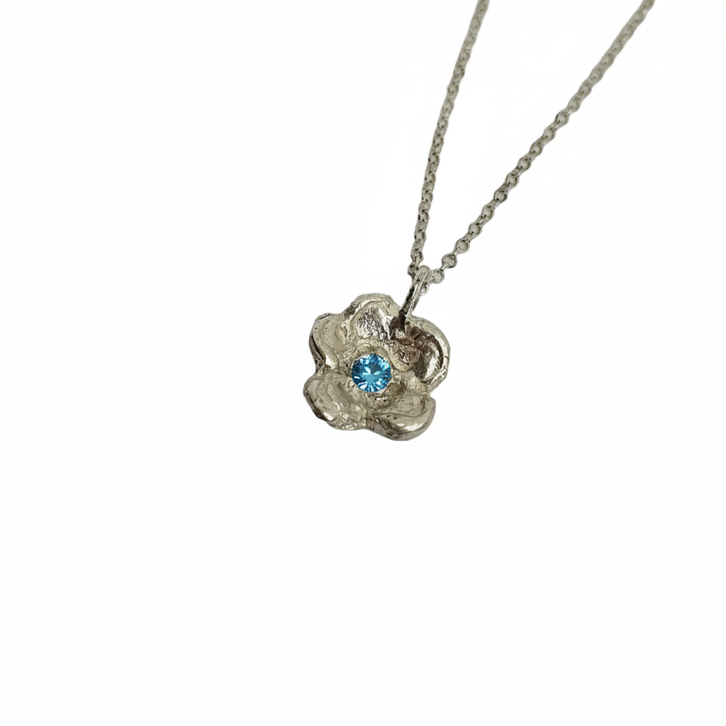 Silver necklace with a floral pendant featuring a red gemstone on a white background