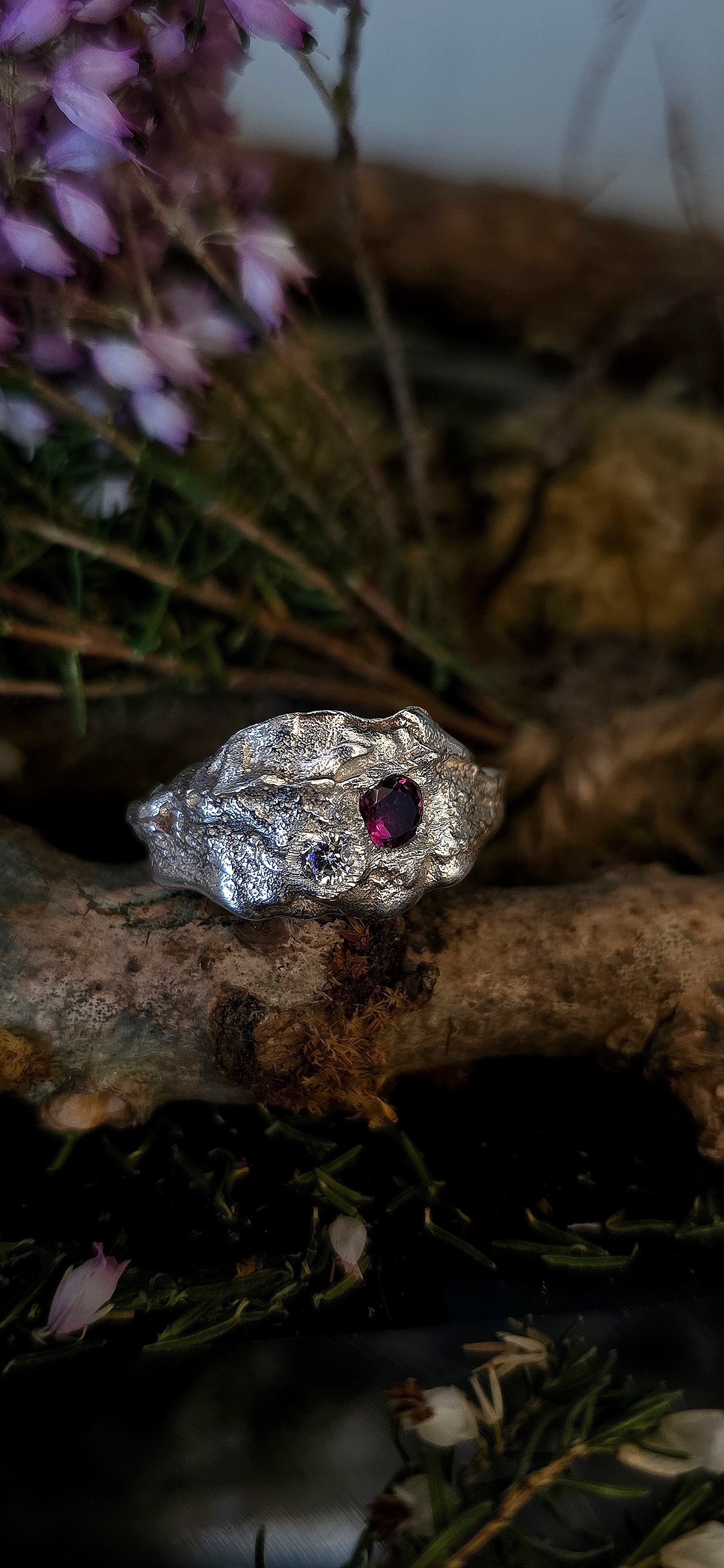 Silver ring with a red gemstone on a natural background