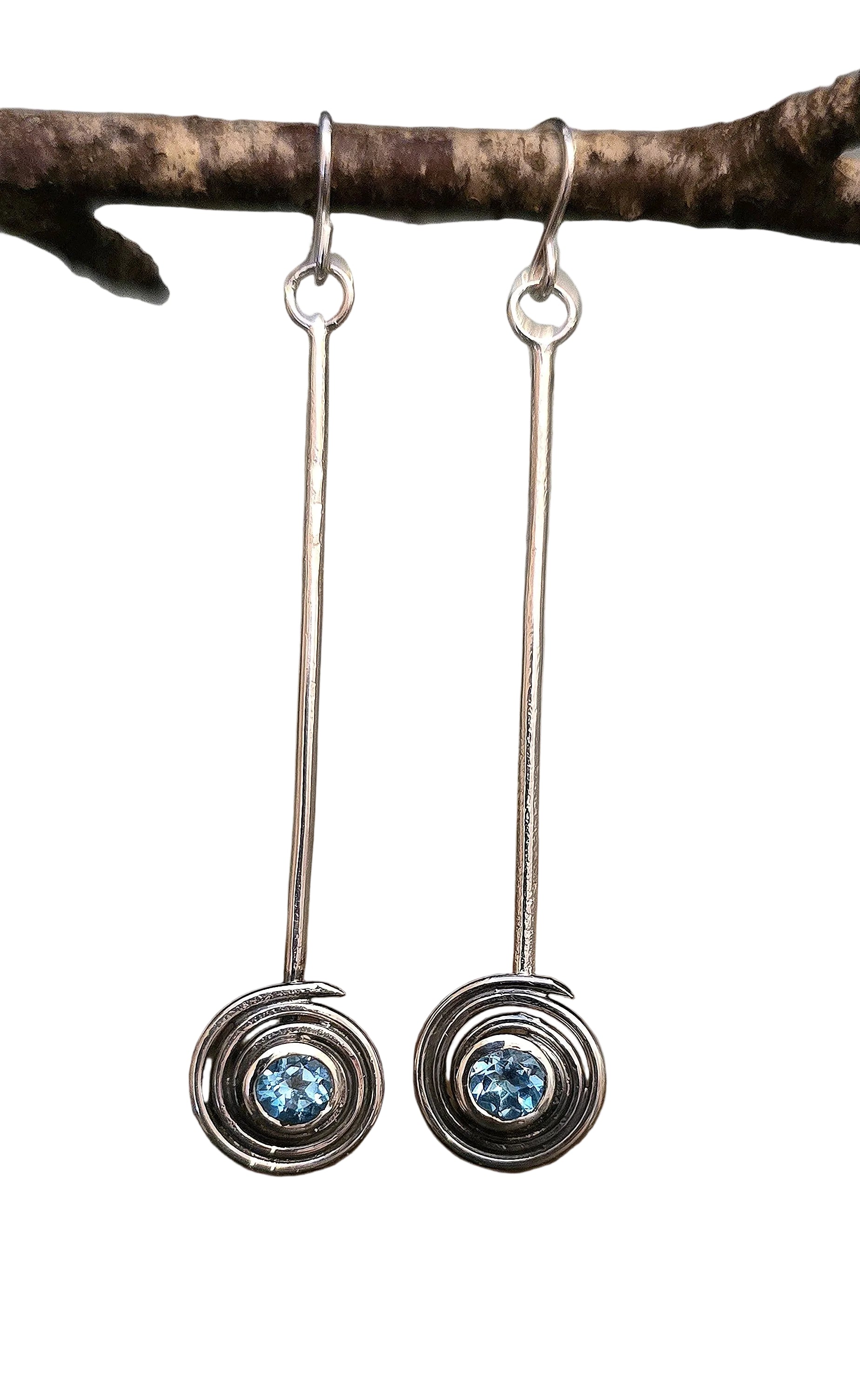 Silver earrings with blue gemstones hanging on a branch. Handmade in Northern Ireland