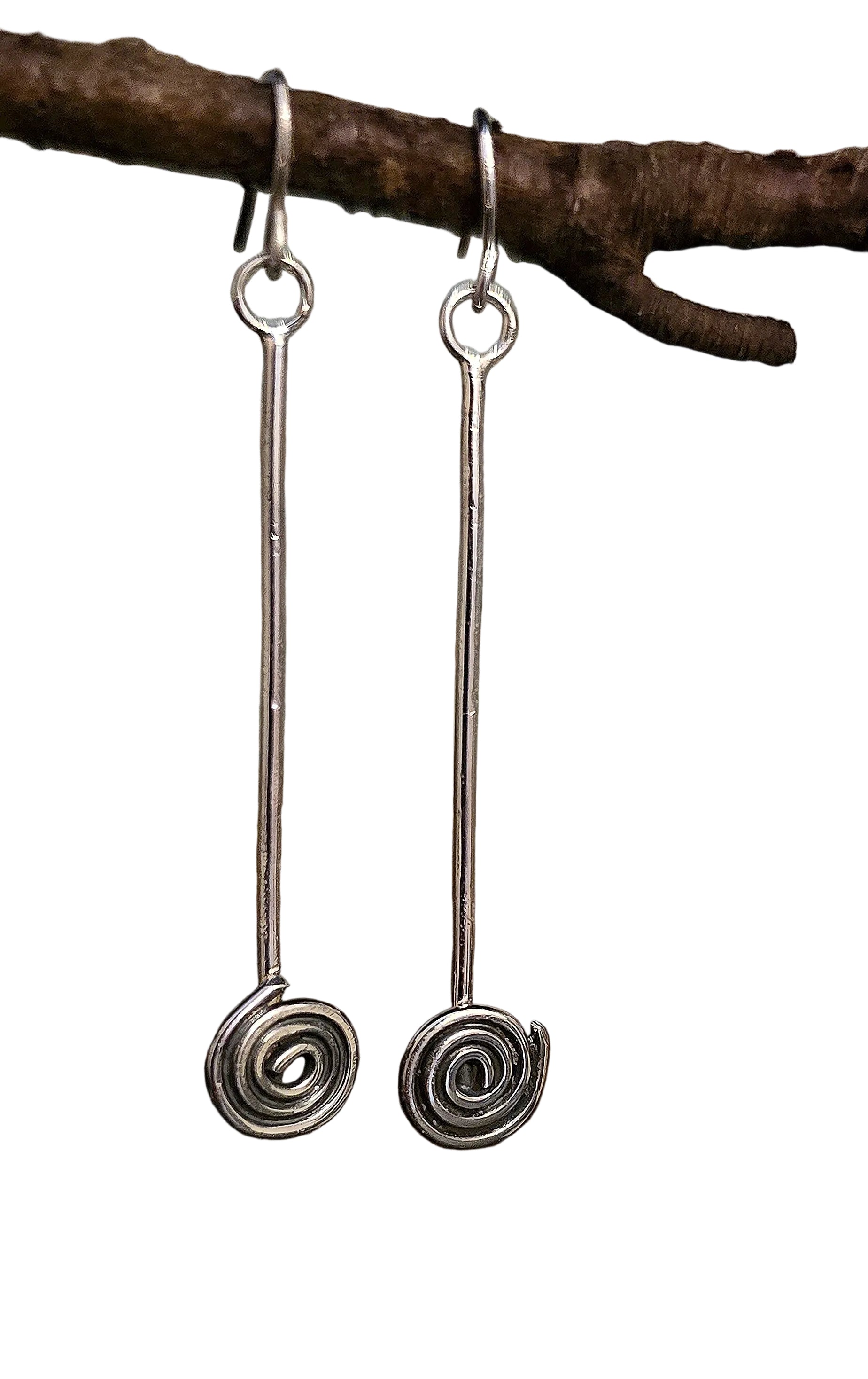 Silver spiral earrings hanging from a branch with a natural background irish jewellery
