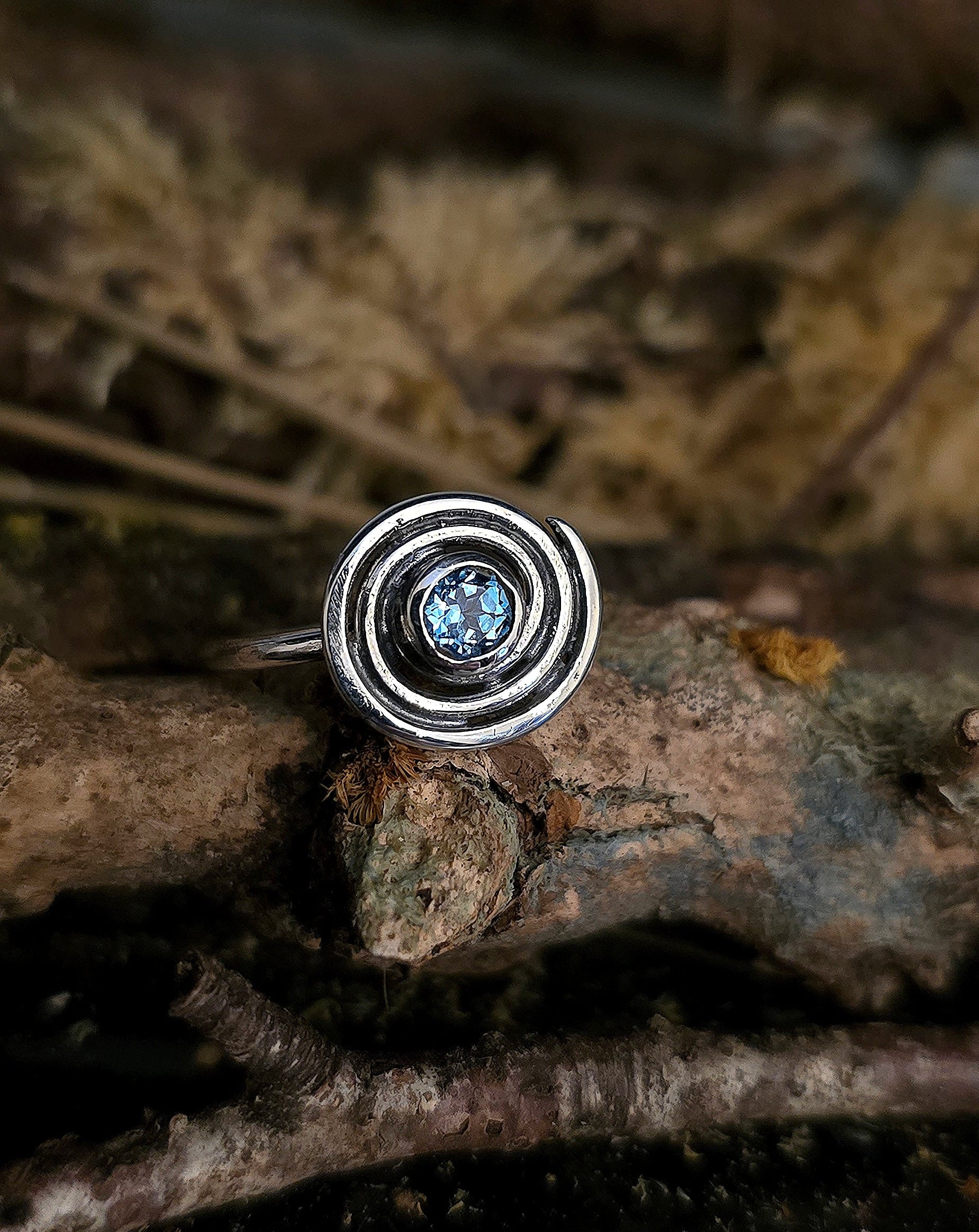 Silver ring with a blue gemstone on a natural background, ancient spiral, irish design