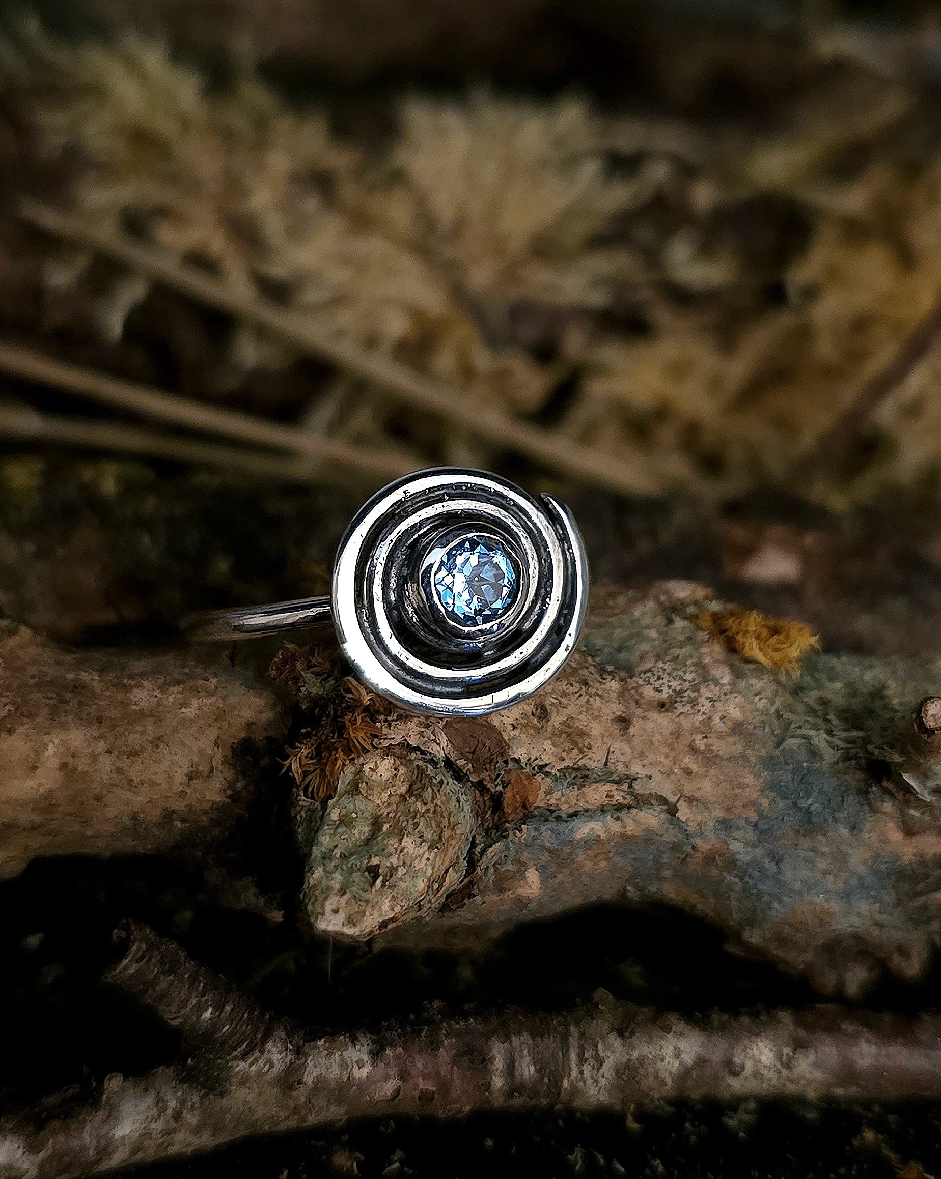 Silver ring with a blue gemstone on a textured surface, ancient  irish design, spiral